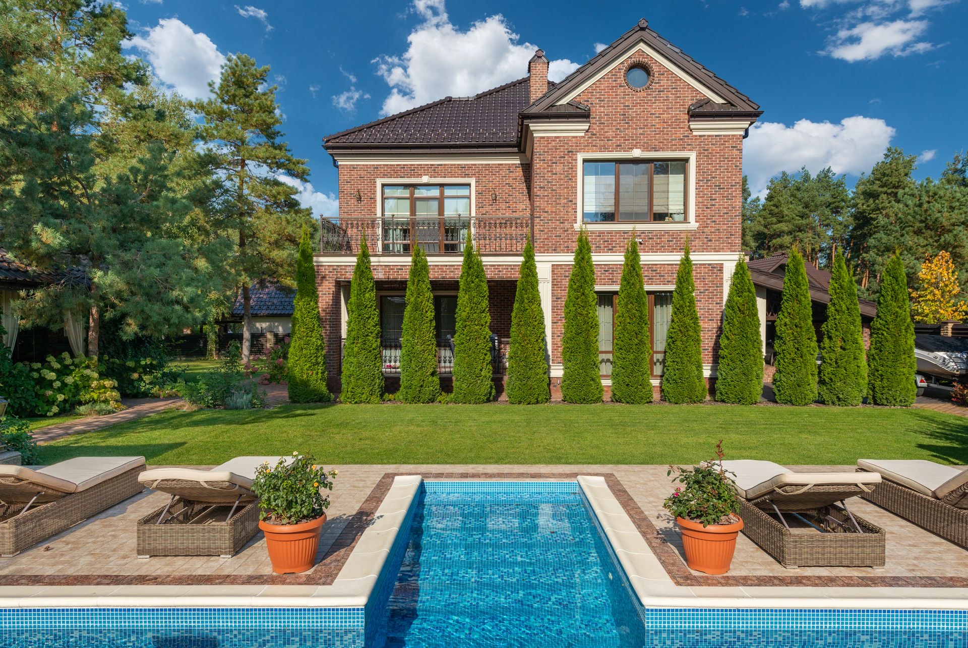A mosaic-tiled pool with loungers beside a brick house