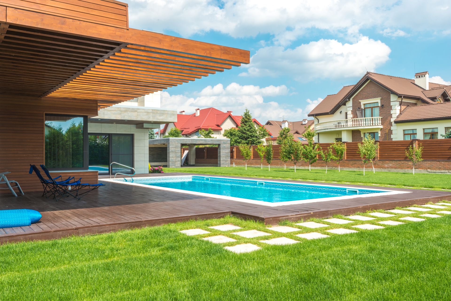 A rectangular backyard pool with a wooden deck at a modern home