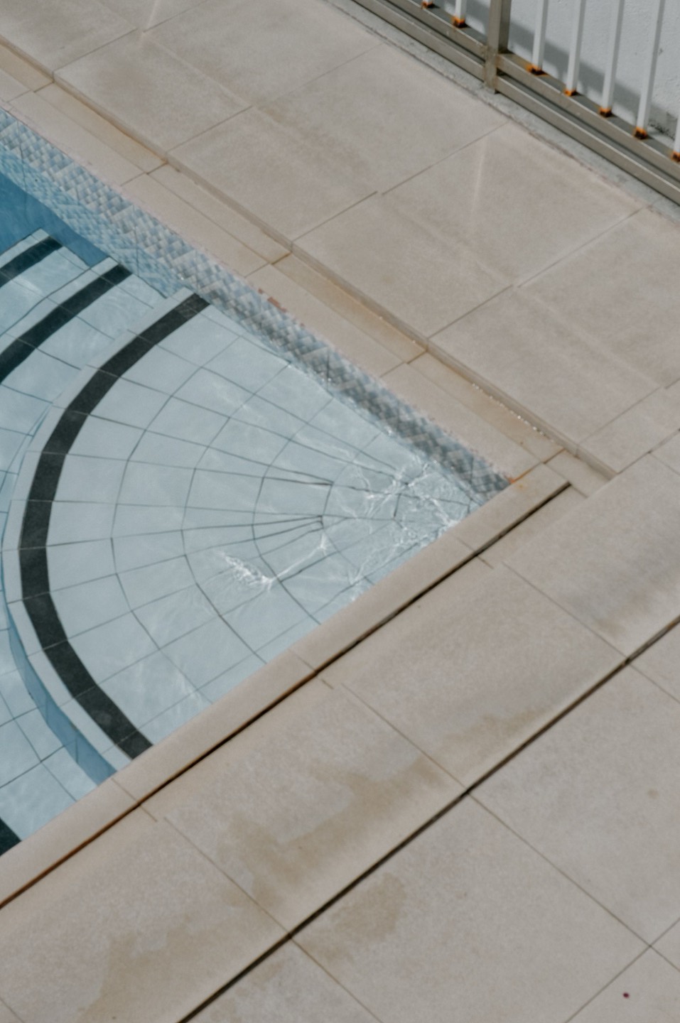 A pool corner showing waterline mosaic tile and stone deck pavers