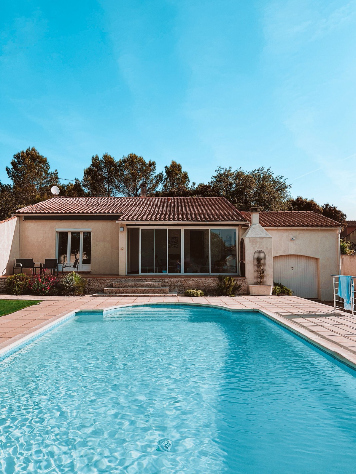 A backyard pool and patio at a tile-roof home