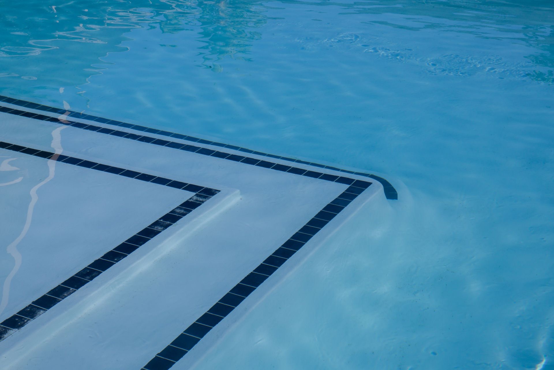 Fresh white pool plaster with navy waterline tile bands